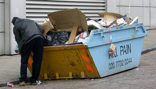 A man rummaging through a dumpster. A man rummaging through a dumpster.